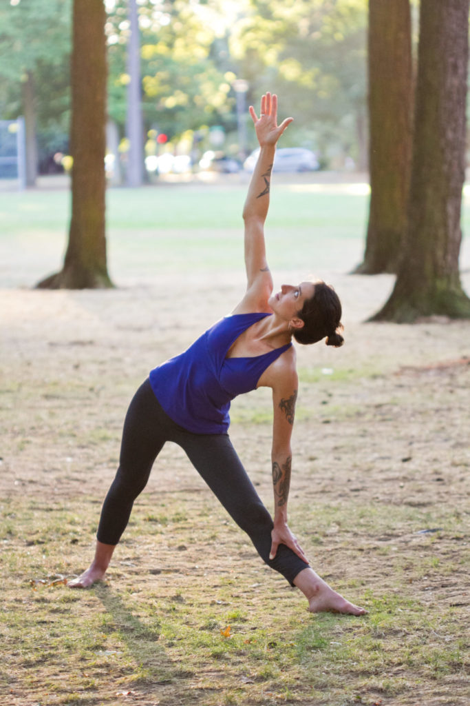 Alix Northup is a triangle pose in a park